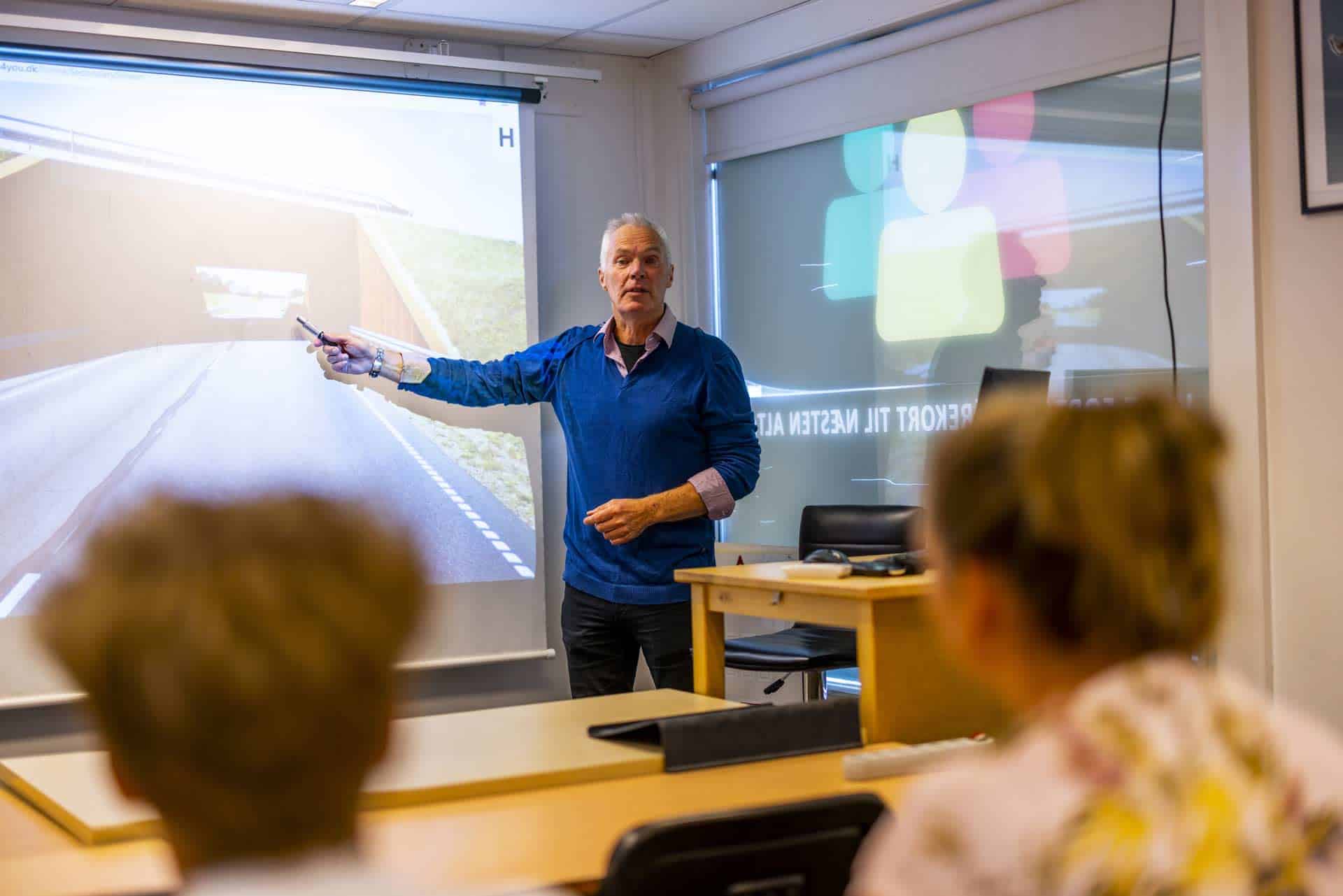 Teoriunderviser peger på tavle med billede af tunnel på vej